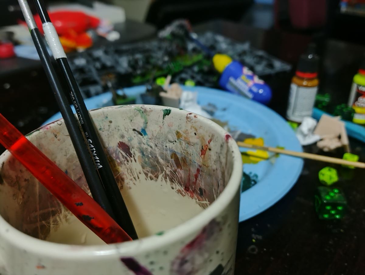 Paint brushes and a paint-stained mug on the hobby desk